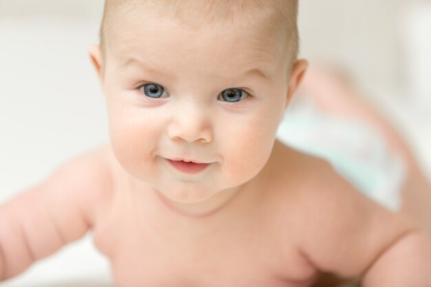 Retrato de un adorable bebé sonriente mantiene la cabeza hacia arriba