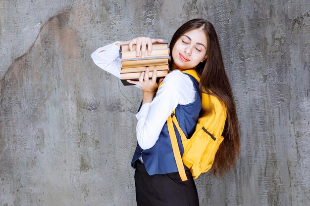 Retrato de adorable estudiante con mochila sosteniendo libros. foto de alta calidad