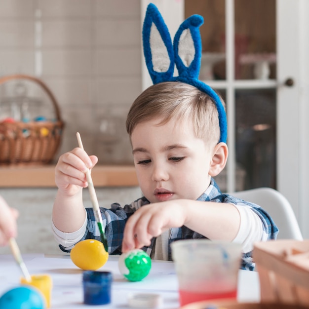 Retrato de adorable niño pintando huevos de pascua