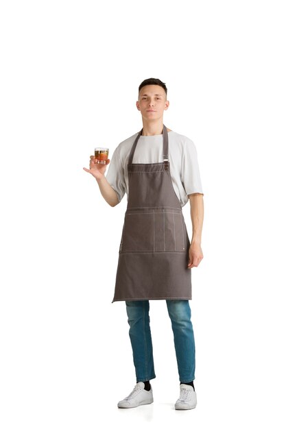 Retrato aislado de un joven barista caucásico o camarero en delantal marrón sonriendo