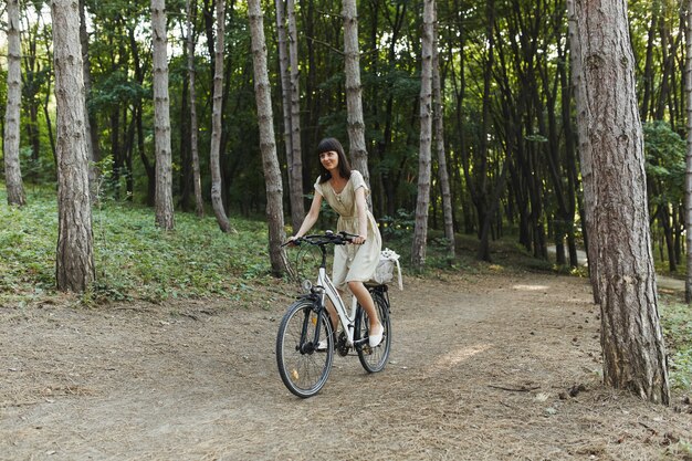 Retrato al aire libre de la atractiva joven morena en bicicleta.