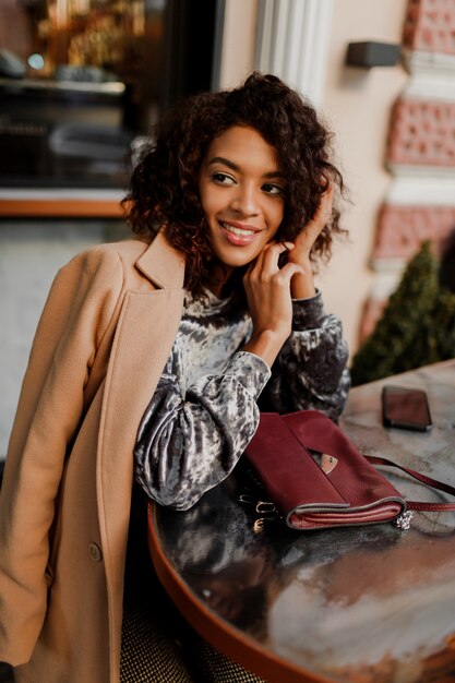 Retrato al aire libre de hermosa mujer negra sonriente con elegantes pelos afro