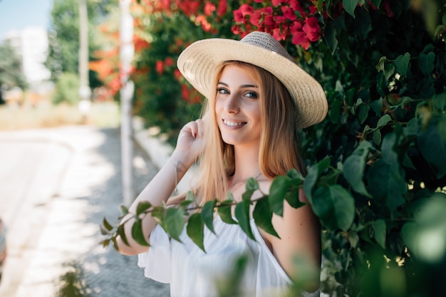 Retrato al aire libre de la joven y bella dama sonriente feliz posando cerca de árbol en flor. Estilo de vida de la ciudad