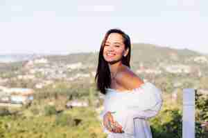 Foto gratuita retrato al aire libre de mujer asiática en vestido blanco con collar y aretes