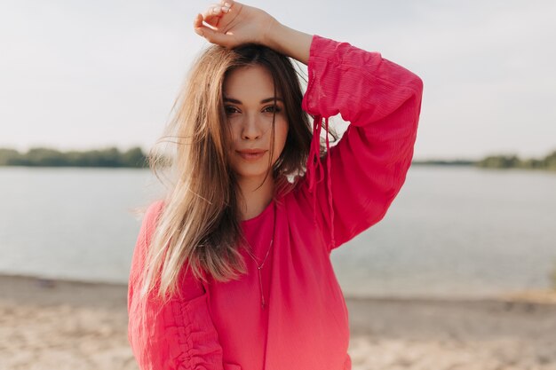 Retrato al aire libre de mujer elegante en traje rosa posando al aire libre en día de verano