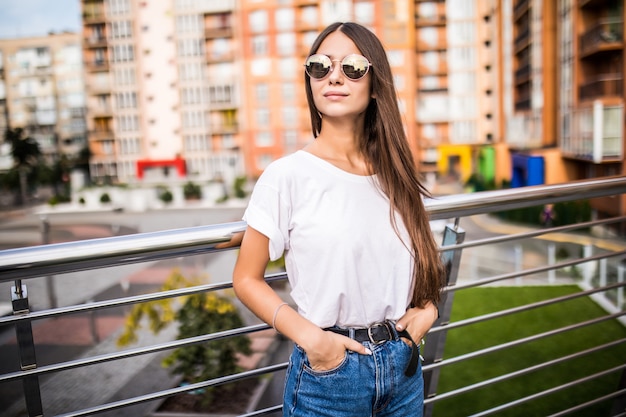 Retrato al aire libre de la mujer joven linda en el puente en ciudad europea.