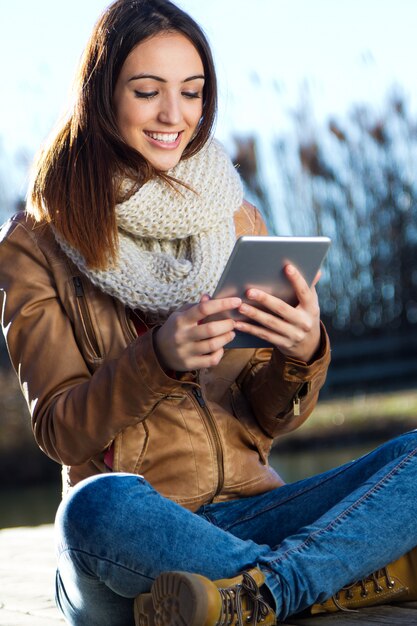 Retrato al aire libre de la mujer joven con la tableta digital