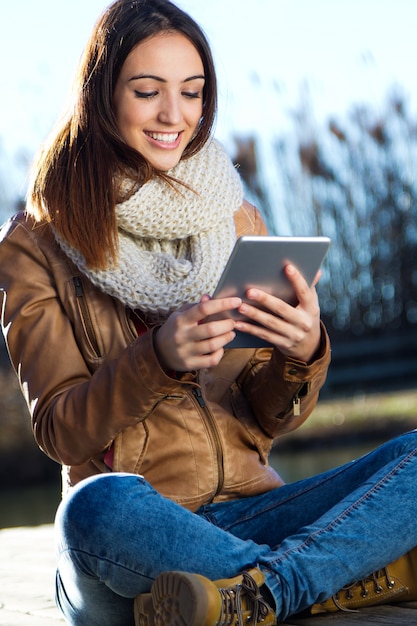 Retrato al aire libre de la mujer joven con la tableta digital