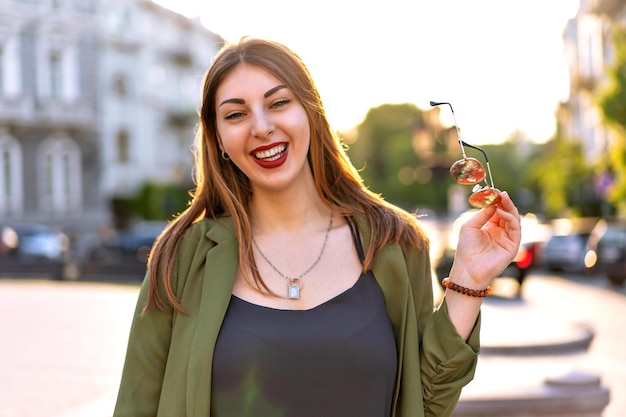 Retrato al aire libre de mujer muy elegante posando en la ciudad de europa, día soleado, atuendo elegante y acsessorizes de cerca.