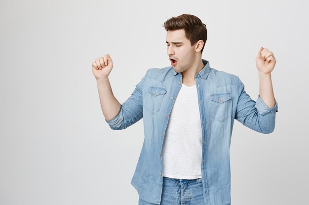 Retrato de alegre atractivo macho europeo sin afeitar que está emocionado y contento de lograr la victoria, aprieta los puños y celebra su éxito, siendo un verdadero campeón. Concepto de felicidad