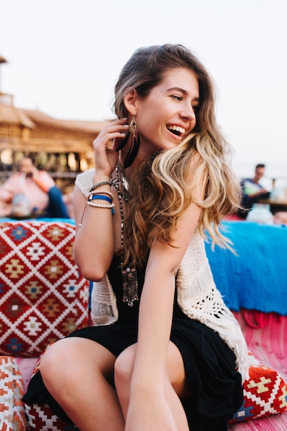 Retrato de alegre chica de pelo largo con estilo divirtiéndose en la fiesta al aire libre con amigos