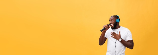 Foto gratuita retrato de un alegre y elegante hombre africano guapo sosteniendo un micrófono y con auriculares puestos