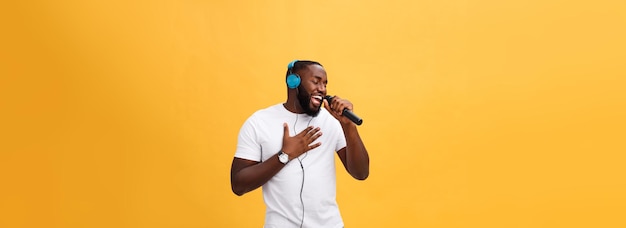 Foto gratuita retrato de un alegre y elegante hombre africano guapo sosteniendo un micrófono y con auriculares puestos