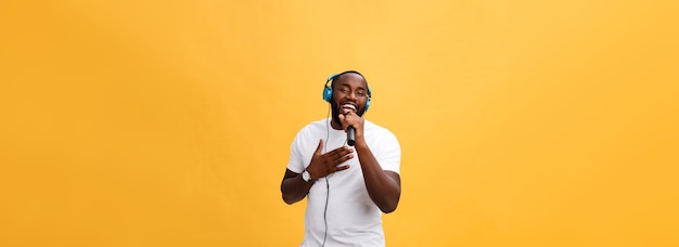 Foto gratuita retrato de un alegre y elegante hombre africano guapo sosteniendo un micrófono y con auriculares puestos