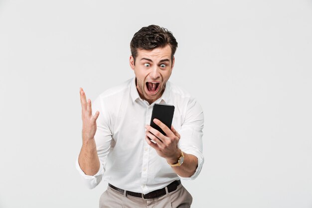 Retrato de un alegre hombre feliz mirando el teléfono móvil