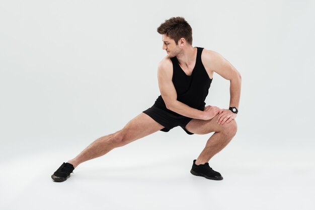 Retrato de un alegre hombre sano calentamiento antes del gimnasio