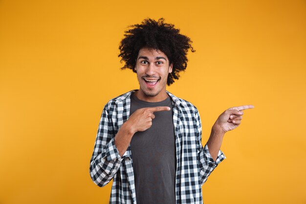 Retrato de un alegre joven africano señalando con el dedo