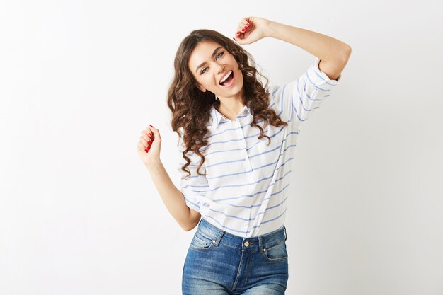 Retrato alegre de joven mujer bonita bailando feliz, expresión de la cara sonriente, cabello largo, estado de ánimo positivo, emocional, traje de estilo hipster, tendencia de la moda de verano, jeans y camisa a rayas, aislado