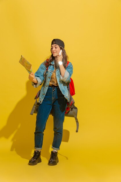 Retrato de una alegre joven turista caucásica aislada en amarillo