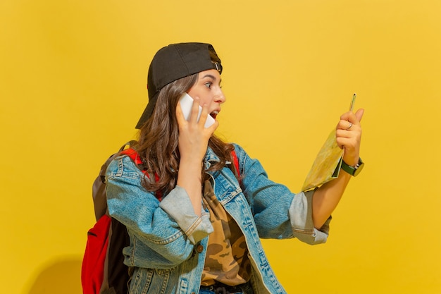 Retrato de una alegre joven turista caucásica aislada en amarillo