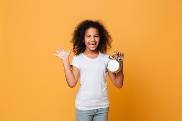 Retrato de una alegre niña africana con despertador