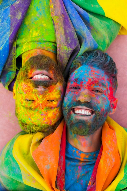 Retrato de alegre pareja gay enamorada manchada en pintura
