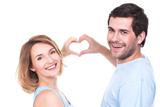 Retrato de alegre sonriente pareja de pie juntos muestran las manos corazón - aislado