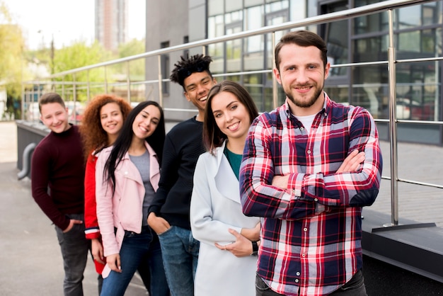 Foto gratuita retrato de alegres amigos multirraciales parados en fila cerca de la barandilla en la calle