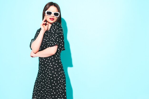 Retrato de alta moda de la joven y bella mujer morena con un bonito vestido de lunares de verano de moda