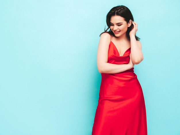 Retrato de alta moda de una joven y bella mujer morena con un bonito vestido de noche rojo de moda Modelo de moda sexy posando en el estudio Mujer de moda aislada