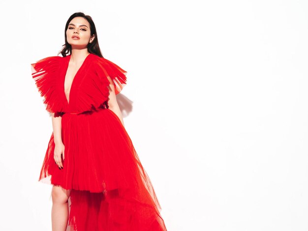 Retrato de alta moda de una joven y bella mujer morena con un bonito vestido rojo de noche esponjoso Modelo de moda sexy posando en el estudio Mujer de moda aislada en blanco