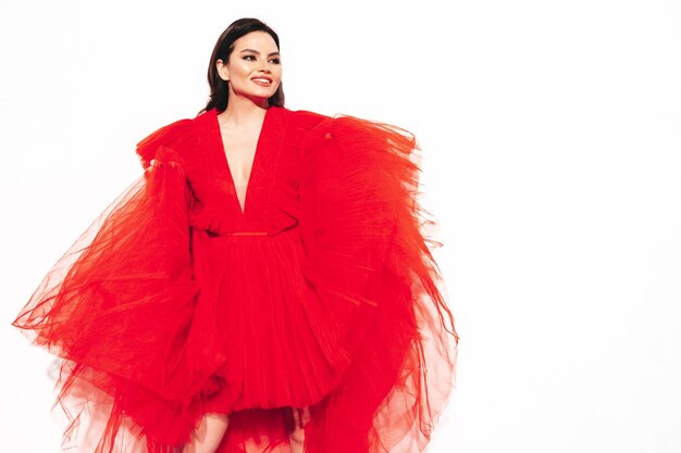 Retrato de alta moda de una joven y bella mujer morena con un bonito vestido rojo de noche esponjoso Modelo de moda sexy posando en el estudio Mujer de moda aislada