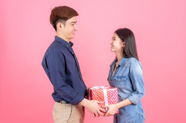 Retrato amigable hombre y mujer adolescentes, están colocados en una caja de regalo roja y sonriendo con un divertido concepto de pareja asiática adolescente