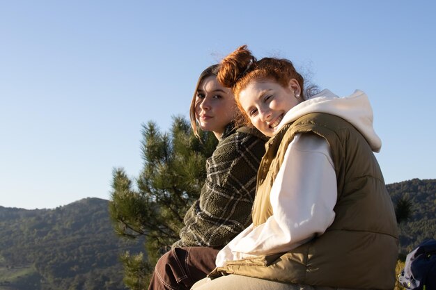 Retrato de amigas felices sentadas juntas en la montaña