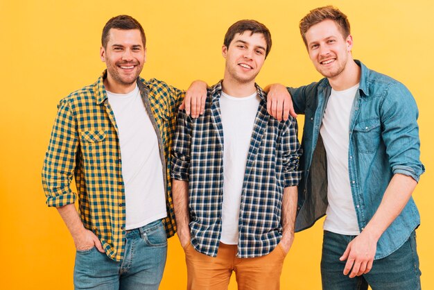 Retrato de un amigo masculino joven sonriente que se opone a fondo amarillo