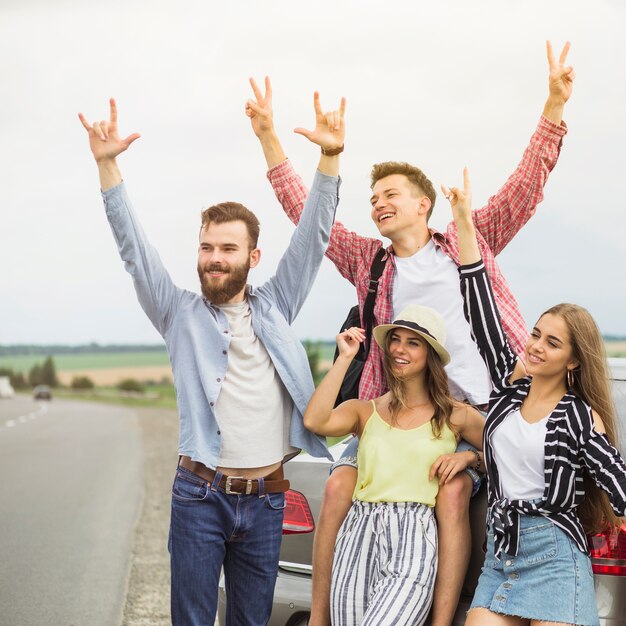 Retrato de amigos disfrutando en carretera cerca del coche