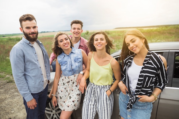 Foto gratuita retrato de amigos felices de pie en el campo cerca del coche