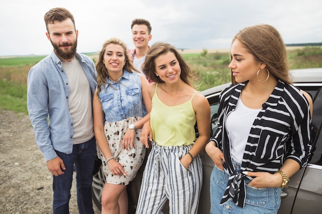 Foto gratuita retrato de amigos felices de pie cerca del coche