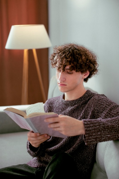 Retrato analógico de un hombre guapo posando en el interior del sofá con un libro