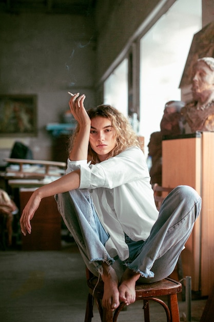 Retrato analógico de una mujer hermosa posando en el interior mientras fuma un cigarrillo