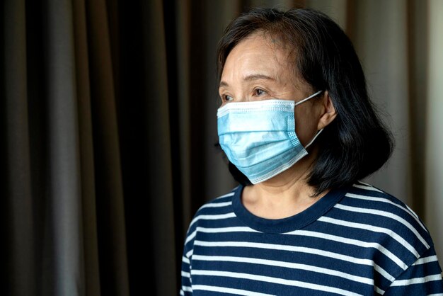 Retrato de anciana asiática anciana con máscara médica facial pandemia coronavirus enfermedad cuarentena en el hogar Concepto de prevención de brotes de Covid19