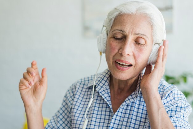 Retrato de una anciana disfrutando de la música en auriculares