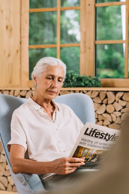 Retrato de una anciana sentada en una silla leyendo el periódico