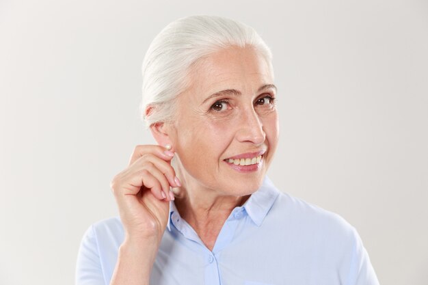 Retrato de anciana sonriente tocando su oreja