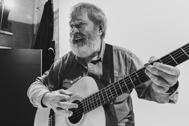 Retrato de un anciano alegre tocando la guitarra interpretando una imagen en blanco y negro Estilo de vida musical
