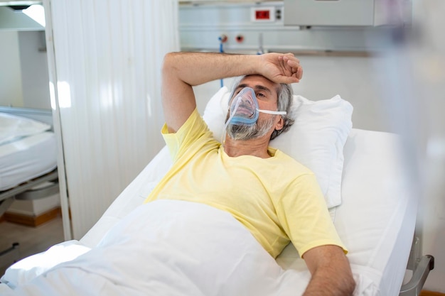 Foto gratuita retrato de un anciano jubilado que respira lentamente con una máscara de oxígeno durante el brote de coronavirus covid19 un anciano enfermo acostado en la cama del hospital recibiendo tratamiento para una infección mortal