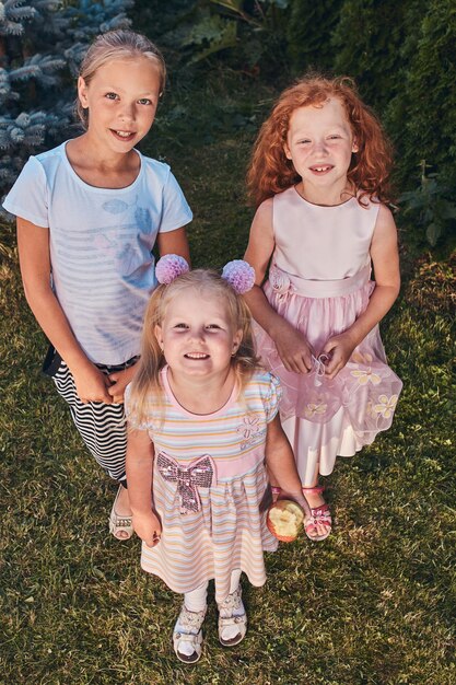 Retrato de ángulo alto de tres novias felices de pie sobre un césped en el parque.