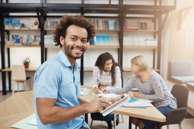 Retrato de apuesto estudiante universitario sentado en reunión con amigos después de estudiar