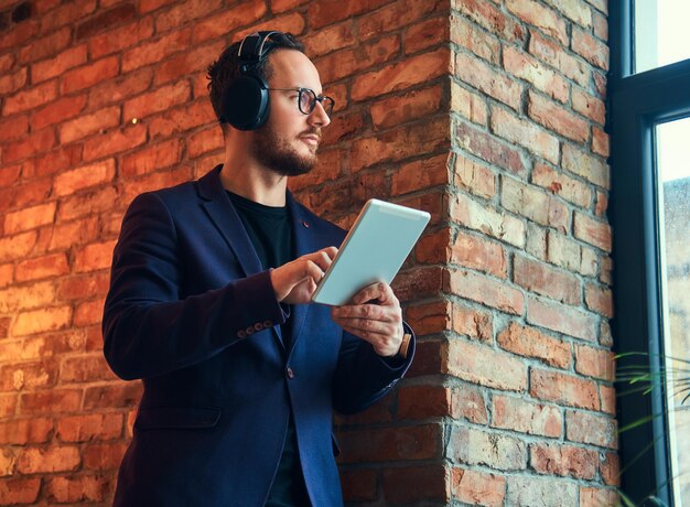 Retrato de un apuesto hombre barbudo con elegante traje listeni