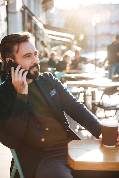 Retrato de un apuesto hombre barbudo hablando por teléfono móvil